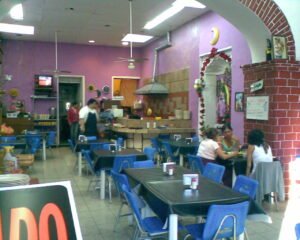 Interior de una fonda mexicana típica, con mesas, sillas y comensales.