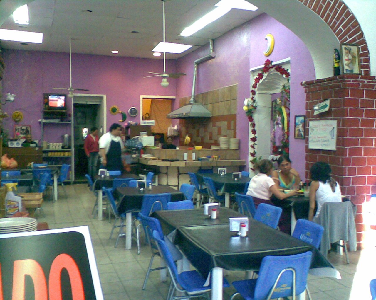 Interior de una fonda mexicana típica, con mesas, sillas y comensales.